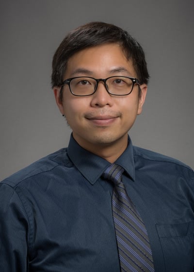 a man in a blue shirt and tie dye on a gray background