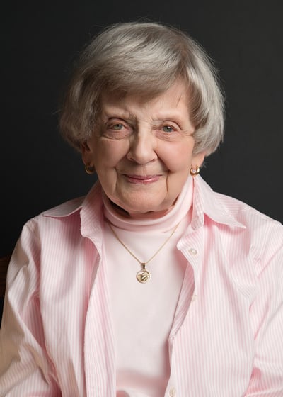 an old woman in a pink shirt and a necklace and earrings