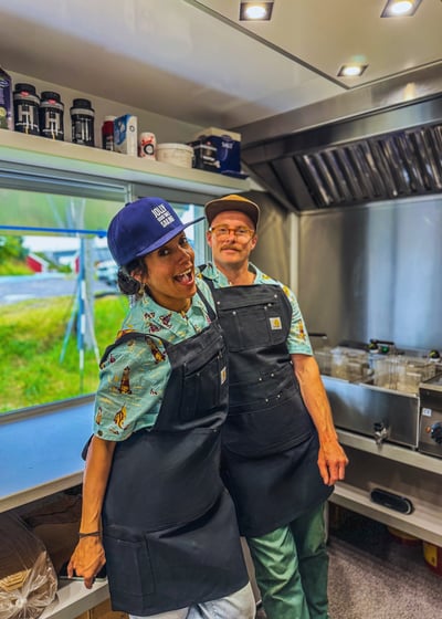 a man and woman in aprons inside the top rated fish and chips food truck located in Hamnøy, Lofoten