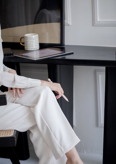 a woman sitting at a desk, holding a pen