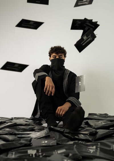 a man in a black shirt and black pants sitting on a pile of black and