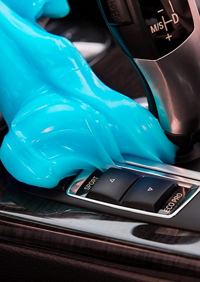 a person in a blue gloved hand held up to a car's dashboard