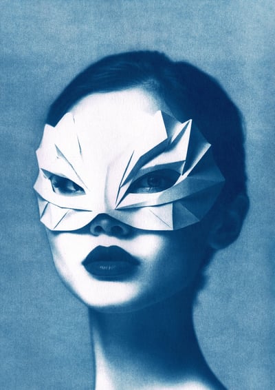 Portrait of a woman with bold lipstick, wearing a geometric paper mask resembling abstract feathers,