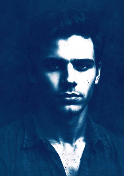 Close-up portrait of a young man with a serious expression, defined features, and short wavy dark ha