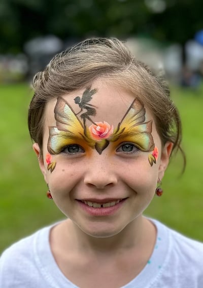 Young girl with face painting of butterfly wings, a fairy and roses. Fairy princess painting