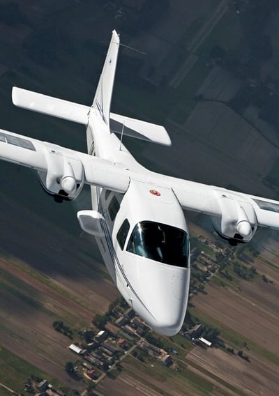 a white airplane flying over a field