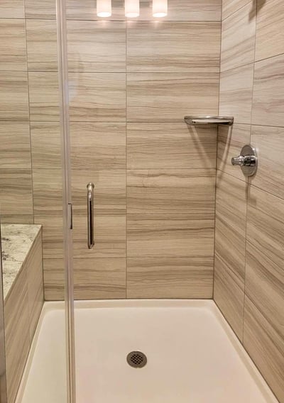 Sparkling clean shower with polished tile walls, fixtures, and glass door.