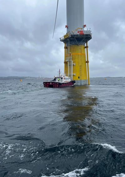 a boat in the water near a wind turbine