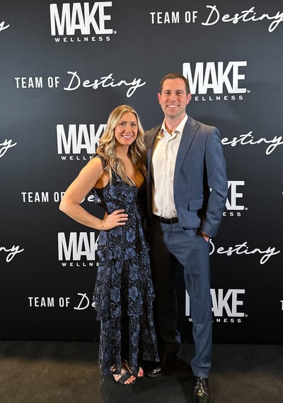 Couple standing in front of Make Wellness backdrop