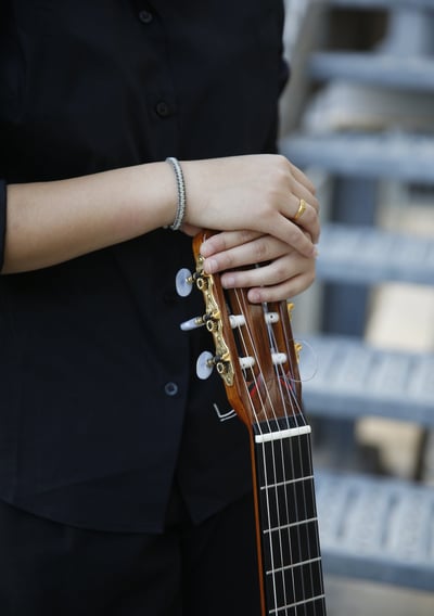 a woman in a suit and tie holds a guitar