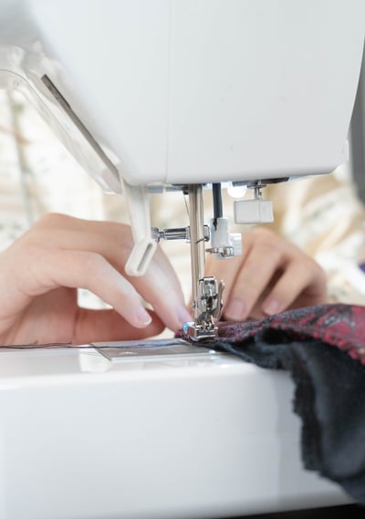 Gros plan sur des mains guidant un tissu sur une machine à coudre