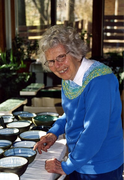 One of our founders, Naoma Powell, pictured with a table full of bowls she made.