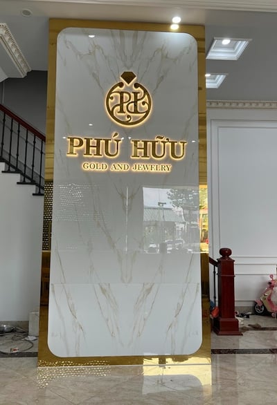 Vách quầy lân bằng chất liệu giả đá kết hợp inox gương vàng 304 có đèn led tạo ánh sáng chân chữ đẹp