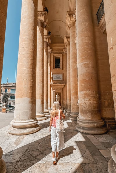 girl walking through mosta rotunda columns