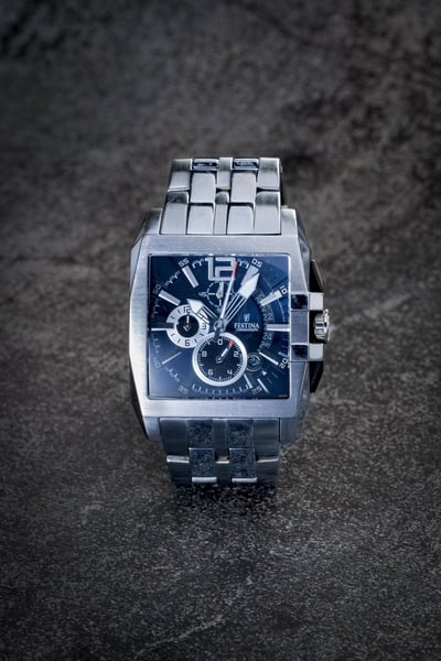 Montre argentée de marque Festina, cadran bleu sur fond pierre noire