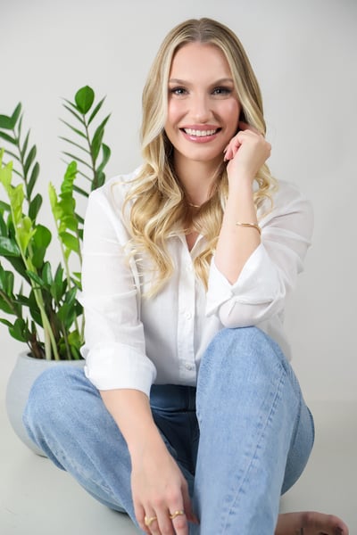 a woman sitting on a white table with a plant in front of her