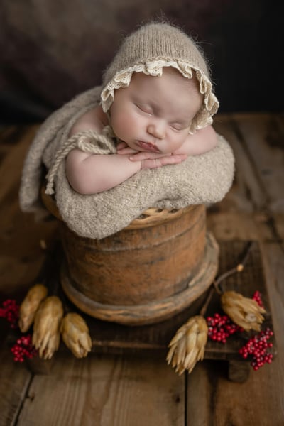 a baby in a basket with a hat on