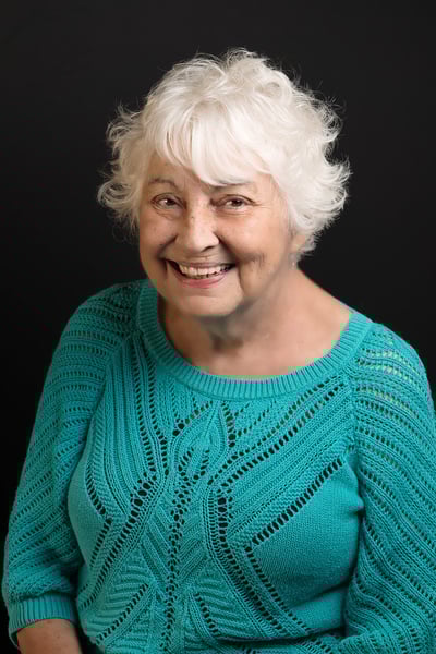 a woman with white hair and a blue sweater with big smile