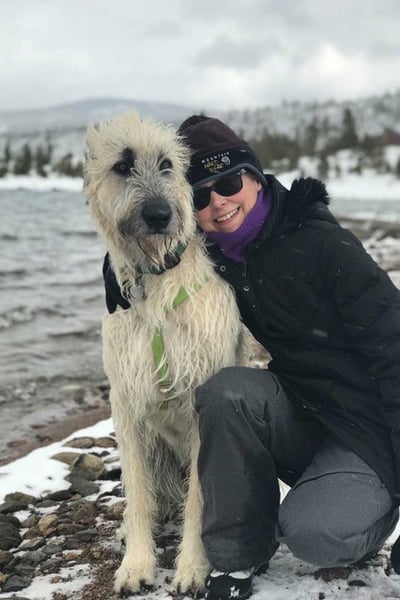 The author hugging her Irish Wolfhound by a snowy mountain lake