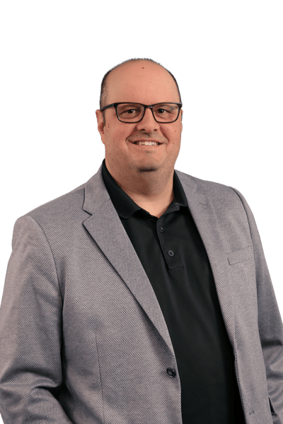 Michael Puccini in a suit and glasses smiling.