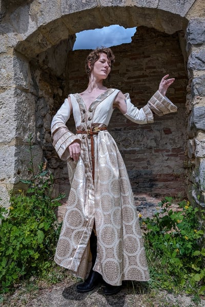Femme en robe blanche et beige médiévale fantastique dans un fond de château en ruines