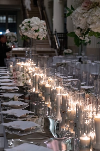 a long mirrored wedding reception table with candles and candles on it