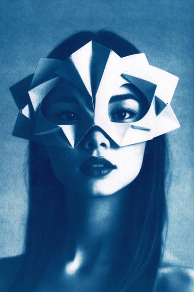 Close-up of a woman with long, straight hair, wearing a geometric paper mask covering her upper face