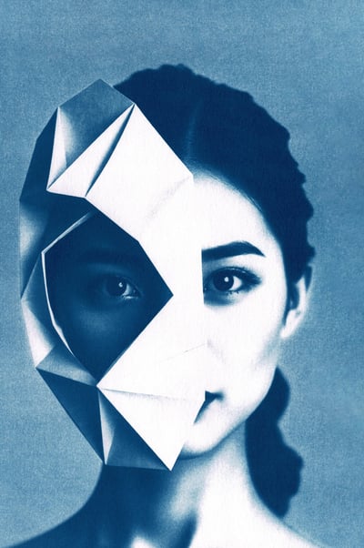 Portrait of a woman with dark hair and light skin, partially obscured by a blue geometric origami ma