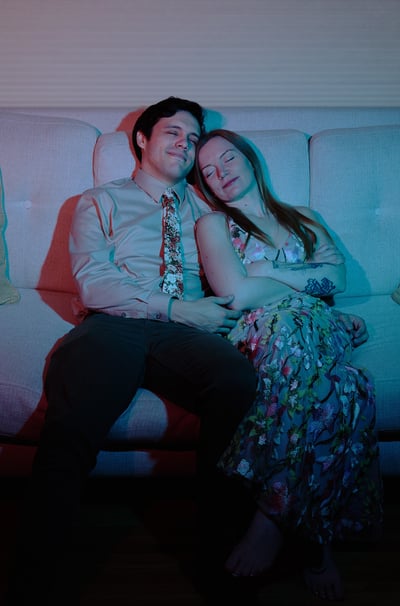 a man and woman sitting on a couch napping