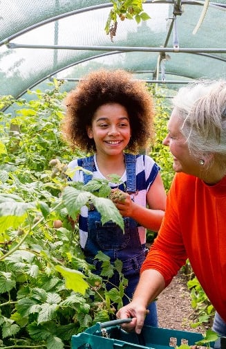 An elderly woman with a preteen girl in the greenhouse