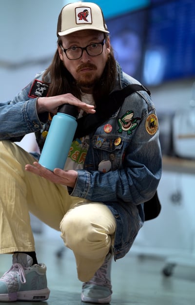 Portrait of a fashionably dressed man holding a blue water bottle