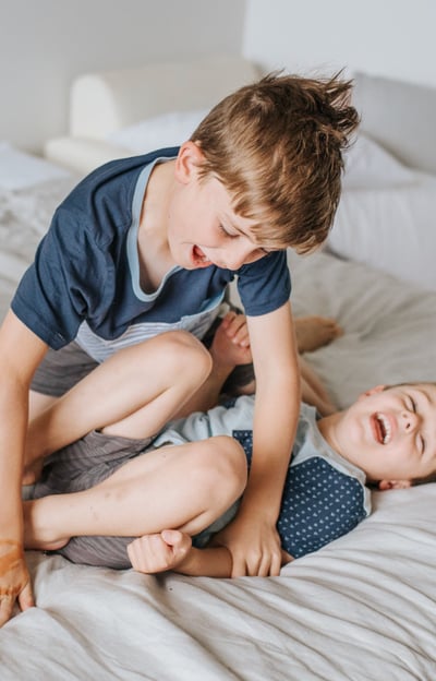Two children play wrestling and smiling