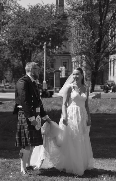 a bride and groom in a field with a scottish flag