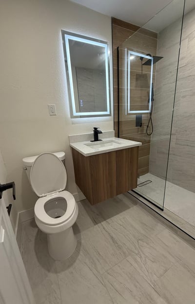 Custom bathroom remodel featuring frameless glass shower, dual sinks, and LED mirror lighting in a C