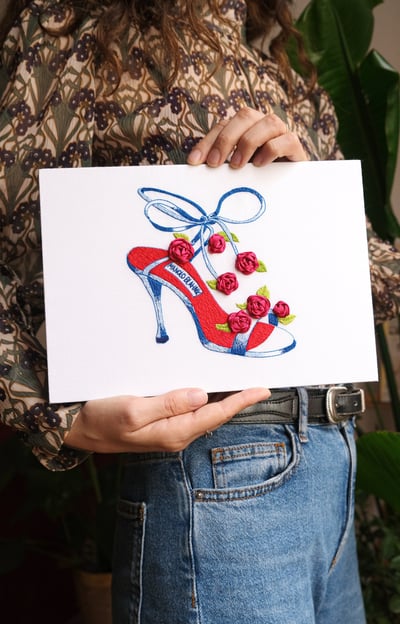 a woman holding a card with a drawing of a shoe