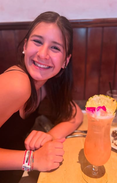 A girl sitting a table drinking a drink