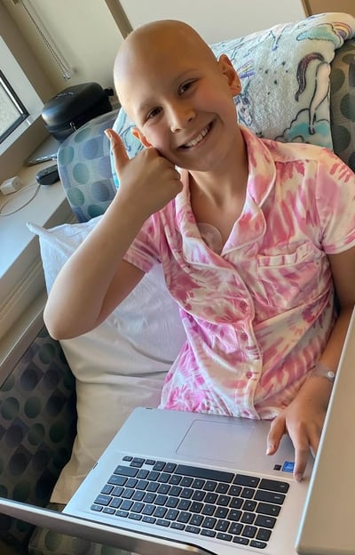 A girl who is fighting cancers giving a thumbs up.