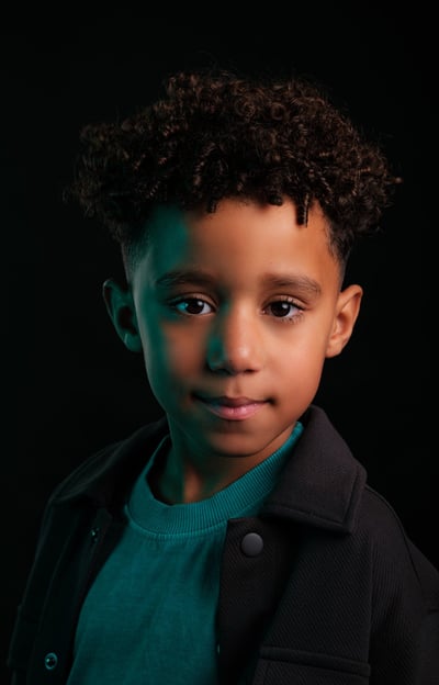 a young boy with a black jacket and a green sweater