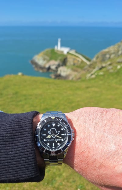 Amser Mon Anglesey black and white metal watch worn next to South Stack, Anglesey, Wales