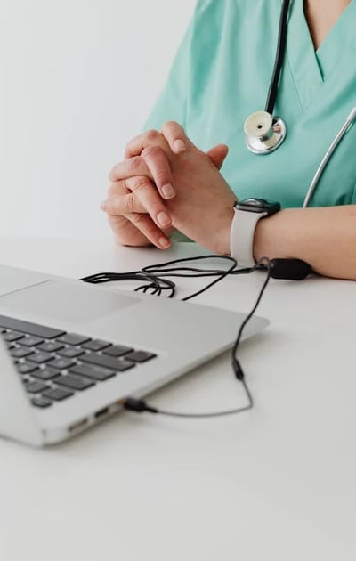 a nurse in scrubs and a stethoscope on a laptop