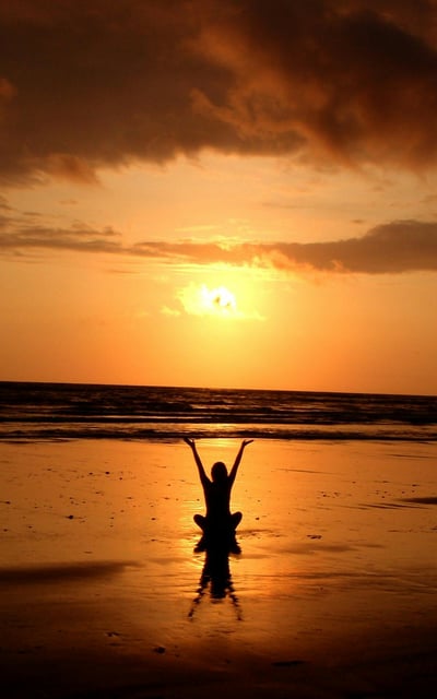 a person standing on a beach with a person holding a kite