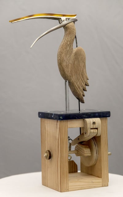 A carved wooden bird whose head and beak are a hair clip. A mechanism to open the beak is visible.