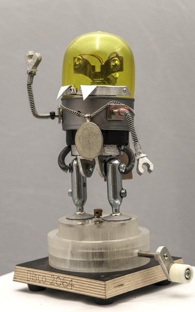 Hand-cranked retro robot model wearing a medallion