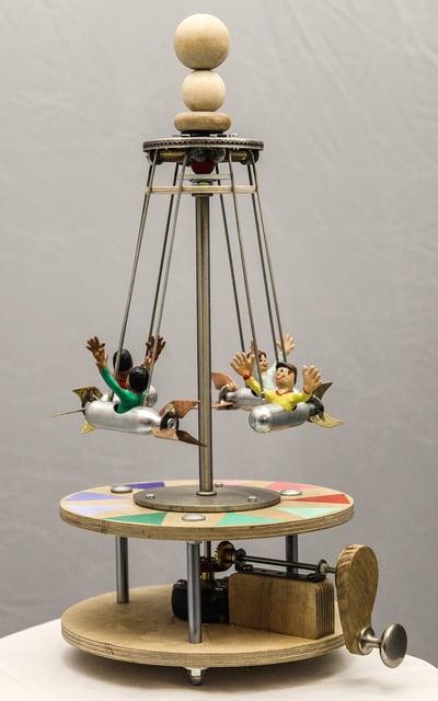 Model carousel with carved figures riding in tiny gas cartridges that will swing out when spun