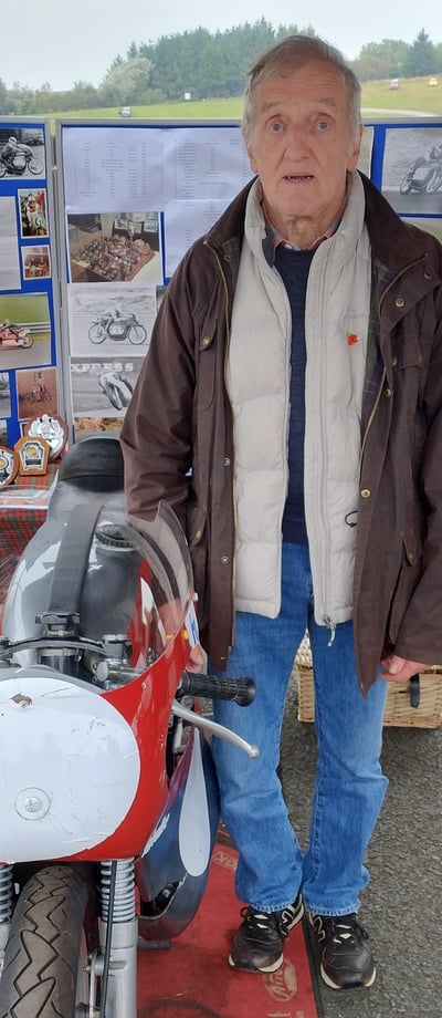 Ronnie standing proudly beside a motorbike, reflecting his passion for racing and the inspiration be