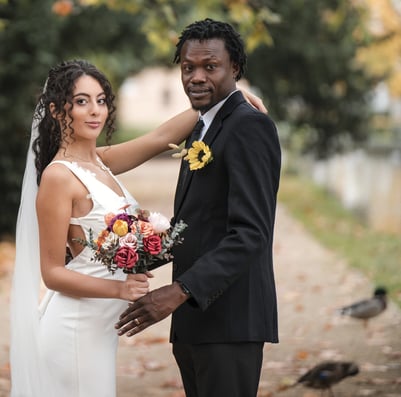 A Bedfordshire bride and groom smile for a photo, surrounded by ducks in a picturesque outdoor setting