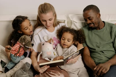 a man and women reading book to two children