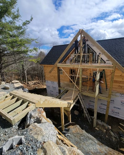 3 construction workers working together to build a staircase to a newly constructed porch for a home