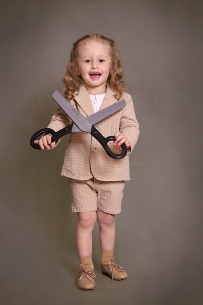 Upsherin boy holding a scissor