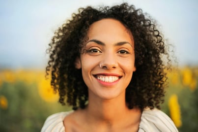 Selective Focus Portrait Photo of Smiling Woman Standing In Front of Sunflower Field